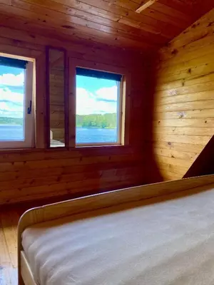 a bedroom with two windows in a wooden cabin at Poilsiadienis in Aukštadvaris