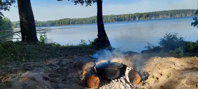 a pot sitting on top of a fire next to a lake at Žalioji vila in Varteliai