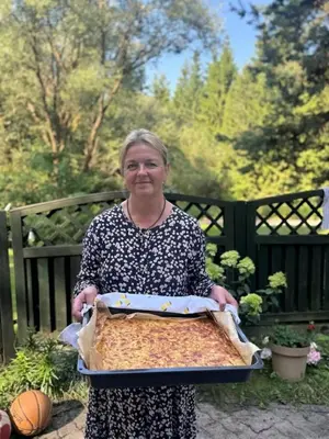 a woman is holding a pan of food at Žalioji vila in Varteliai