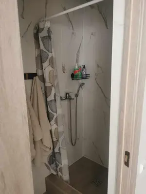 a shower with a shower curtain in a bathroom at Lauros & R apartamentai in Panevėžys