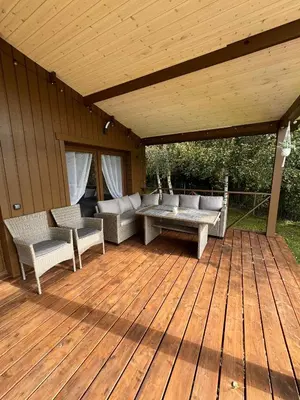 a wooden deck with couches and a table at Poilsio Pieva in Ąžuolų Būda