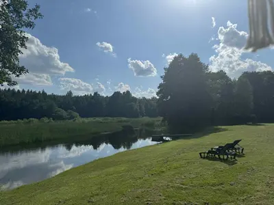 a bench sitting on the grass next to a river at Poilsio Pieva in Ąžuolų Būda