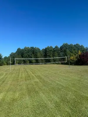a volleyball net in a field with trees in the background at Poilsio Pieva in Ąžuolų Būda