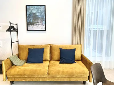 a yellow couch with blue pillows in a living room at White Lotus Apartment 13 by Reside Baltic in Vilnius