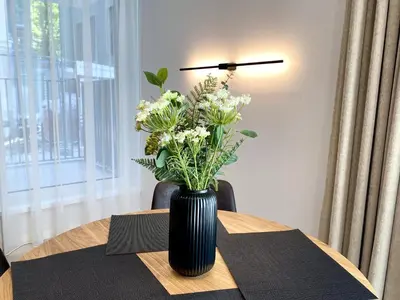 a black vase with white flowers on a table at White Lotus Apartment 13 by Reside Baltic in Vilnius