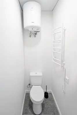 a white bathroom with a toilet and a light at Central Cozy 1Bedroom Apartment with Sofa Bed - Sleeps 4 in Vilnius