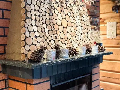 a fireplace with a bunch of logs and pine cones at Pirtelė Rykštelė in Karmėlava