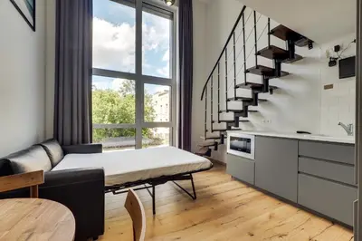 a living room with a bed and a staircase at Uptown Lofts in Vilnius
