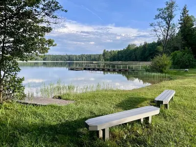 two benches sitting in the grass near a lake at Tytuvėnai-trumpalaikė nuoma in Tytuvėnai