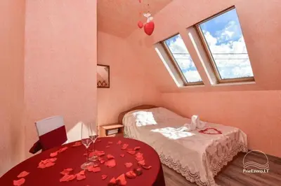 a bedroom with a bed and a table with flowers on it at Tytuvos upelio Krantinė in Tytuvėnai