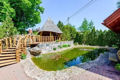 a garden with a pond and a gazebo at Tytuvos upelio Krantinė in Tytuvėnai