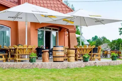 a patio with chairs and umbrellas in front of a building at Tytuvos upelio Krantinė in Tytuvėnai