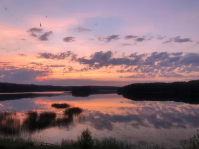 a sunset over a lake with trees and clouds at Poilsiadienis in Aukštadvaris