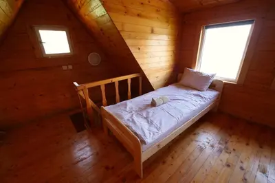 a bedroom with a bed in a wooden cabin at Poilsiadienis in Aukštadvaris