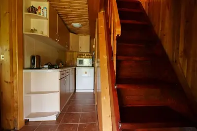 a kitchen with a staircase leading up to a kitchen with white cabinets at Poilsiadienis in Aukštadvaris