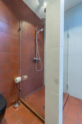 a shower in a bathroom with red tiles at Jazz Old Town apartment with AC in Kaunas