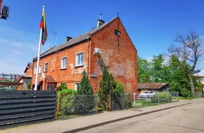 a red brick building with a flag on it at Red House Corner in Marijampolė