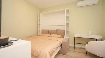 a small bedroom with a bed and a desk at Red House Corner in Marijampolė