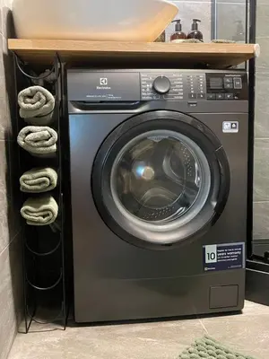 a washing machine in a room with a shelf at Moss Suite in Druskininkai