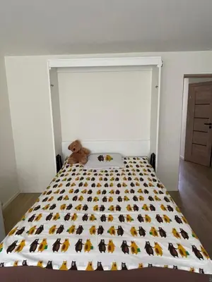 a teddy bear sitting on a bed in a bedroom at Moss Suite in Druskininkai