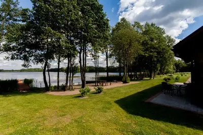 a yard with a table and chairs and a lake at Vila Viesai in Trakai