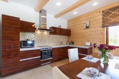a kitchen with wooden cabinets and a wooden table with a dining room at Vila Viesai in Trakai
