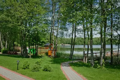 a park with a lake and trees and a path at Vila Viesai in Trakai