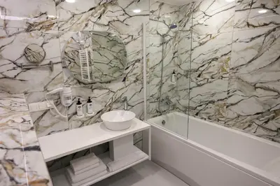 a bathroom with a marble wall with a sink and a shower at Suncity Hotel & SPA in Šiauliai