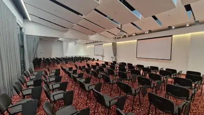an empty lecture hall with chairs and a screen at Suncity Hotel & SPA in Šiauliai