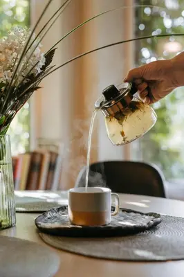 a person pouring coffee into a cup on a table at Upės Namai Jonami in Anykščiai