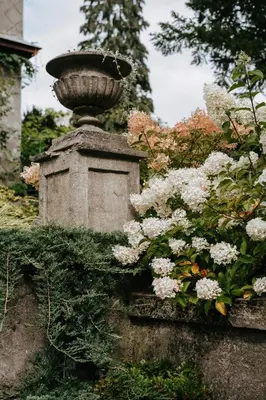 a stone statue with flowers in a garden at Upės Namai Jonami in Anykščiai