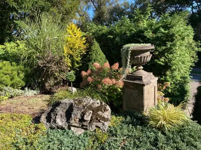 a garden with a statue in the middle at Upės Namai Jonami in Anykščiai