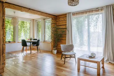 a living room with a table and chairs and windows at Upės Namai Jonami in Anykščiai
