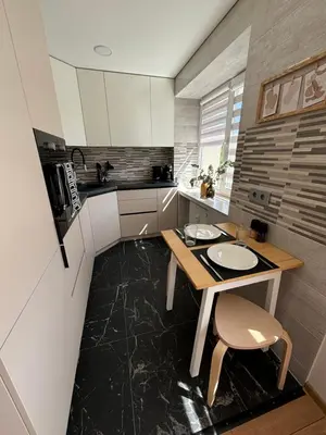 a small kitchen with a wooden table and a table and chairs at Suite Dreams in Kėdainiai