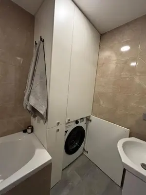 a bathroom with a washing machine in a white cabinet at Suite Dreams in Kėdainiai