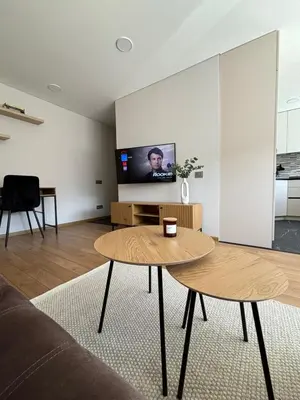 a living room with a table and a flat screen tv at Suite Dreams in Kėdainiai