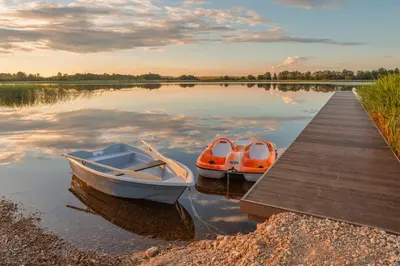 two boats sitting on the water next to a dock at Comfort Villas in Ukmergė