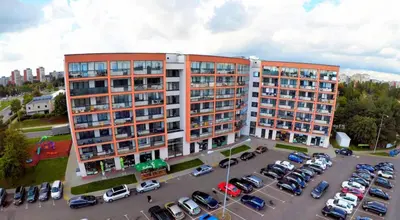 a large building with cars parked in a parking lot at Sausio 13 Apartamentas in Vilnius