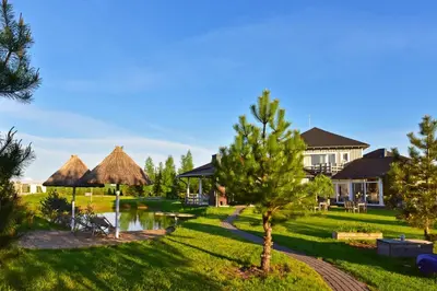 a resort with a pond and trees and a house at Cozy stay by Kaunas vila 9Vėjai in Girininkai