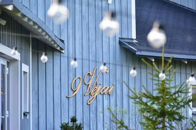 a sign on the side of a blue building at Cozy stay by Kaunas vila 9Vėjai in Girininkai