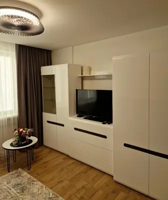 a white cabinet with a television in a living room at Apartamentai AKVIJOLA in Vilkaviškis