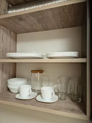 a shelf with plates and bowls and glasses on it at Apartamentai AKVIJOLA in Vilkaviškis