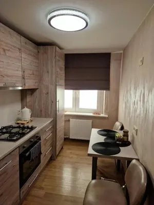 a kitchen with a stove and a table with chairs at Apartamentai AKVIJOLA in Vilkaviškis