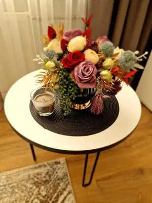 a vase of flowers on a table with a candle at Apartamentai AKVIJOLA in Vilkaviškis