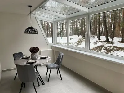 a dining room with a table and chairs and windows at Peaceful Apartment Lazdynai in Vilnius