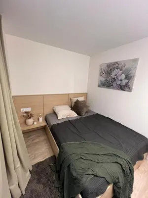 a small bedroom with a bed and a curtain at Peaceful Apartment Lazdynai in Vilnius