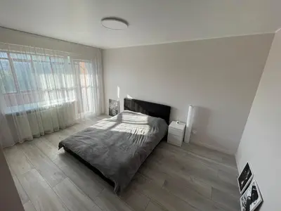 a bedroom with a bed in a white room at Karoliniškių apartamentai in Vilnius