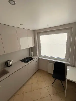 a kitchen with white cabinets and a window at Karoliniškių apartamentai in Vilnius