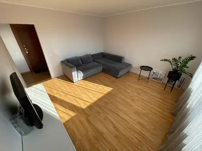 a living room with a couch and a wooden floor at Karoliniškių apartamentai in Vilnius