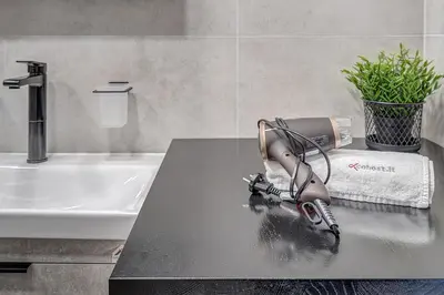 a hair dryer sitting on a counter in a bathroom at cohost I Newly Built Apartments by Historical Bastion Wall, Self check in in Vilnius